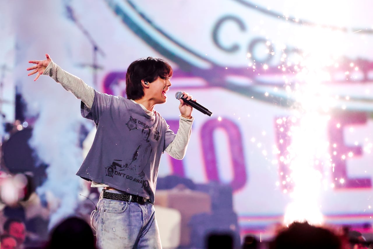 A man holding a microphone sings passionately on stage.