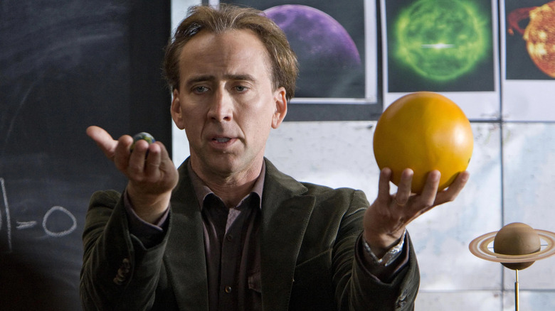 John Koestler holding a picture of the Earth and a model of the Sun in Knowing