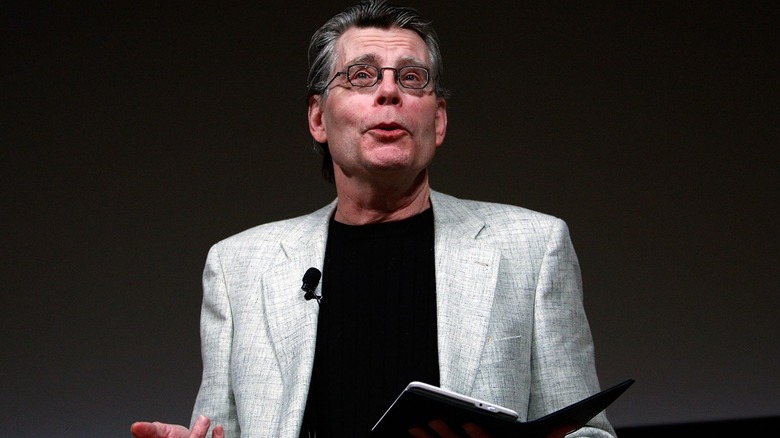 Stephen King on stage reading from a Kindle