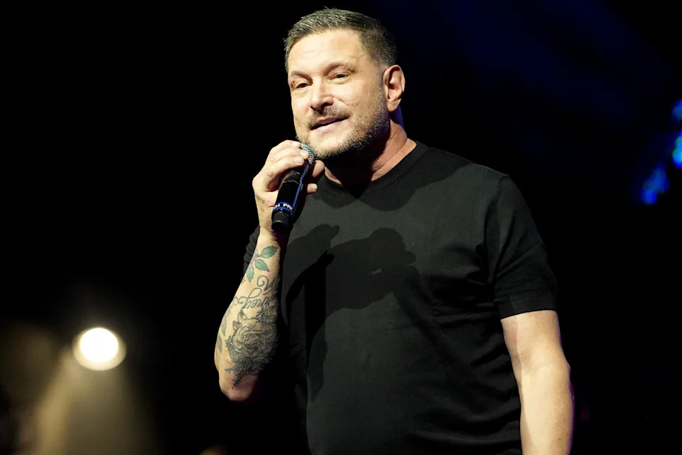 Ty Herndon in a black shirt holding a microphone.